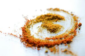 A vibrant array of colorful spices including turmeric and curry powder on a white background.