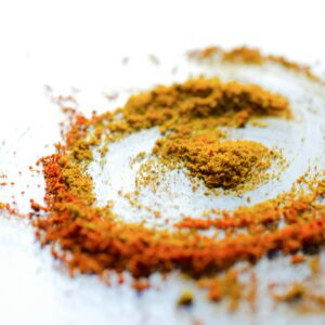 A vibrant array of colorful spices including turmeric and curry powder on a white background.