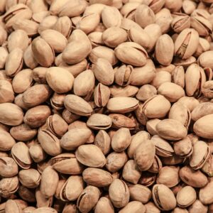 A detailed close-up image of pistachio nuts, showcasing their natural texture and earthy tones.