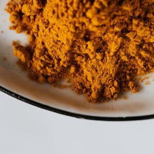 A vibrant close-up image of ground turmeric spice on a ceramic plate.