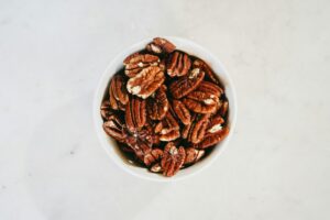 Top view of a bowl filled with healthy pecan nuts on a light surface, ideal for nutrition themes.
