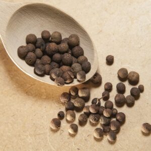 Close-up view of allspice peppercorns on a wooden spoon, perfect for culinary and spice themes.