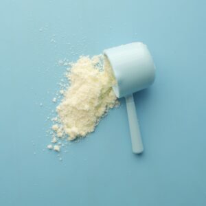 White powder spilled from a scoop on bright blue background. Clean and minimalistic food photo.